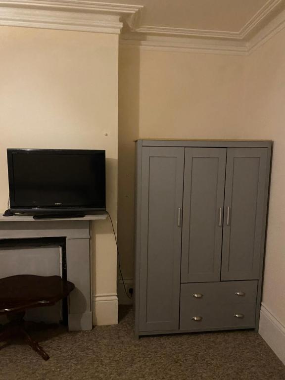 ein Wohnzimmer mit einem TV und einem Schrank in der Unterkunft Palace in Crystal Palace