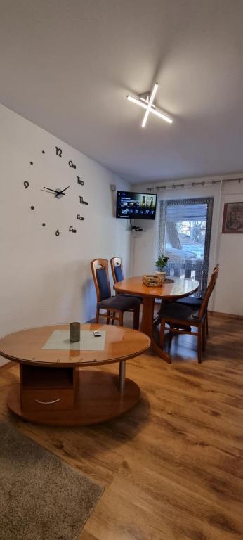 sala de estar con mesa y reloj en la pared en Apartmaji Medved, brezplačno parkiranje en Tacen