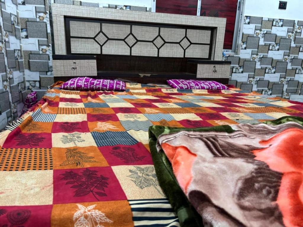 a bed with a colorful quilt on top of it at GRG Sunrise Plaza Deoghar in Deoghar