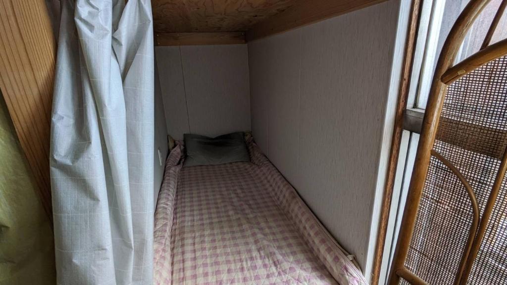 八戸市にあるHamburger restaurant Big foot - Vacation STAY 16323の小さなカーテン付きの小さな部屋のベッド1台分です。