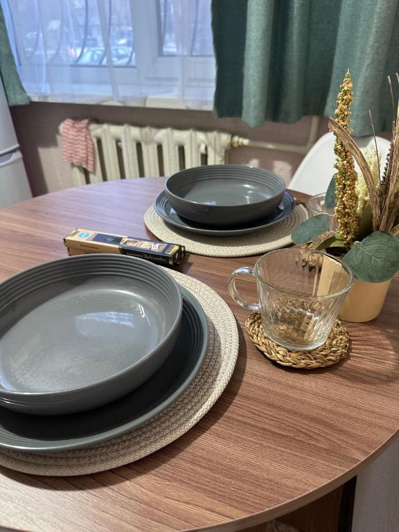 une table en bois avec des assiettes et des bols noirs dans l'établissement Муканова 6/2, à Karaganda