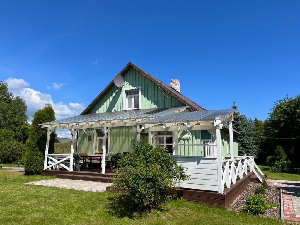 une maison verte et blanche avec une terrasse couverte dans l'établissement Rähni Guesthouse Lake Peipsi, à Vilusi