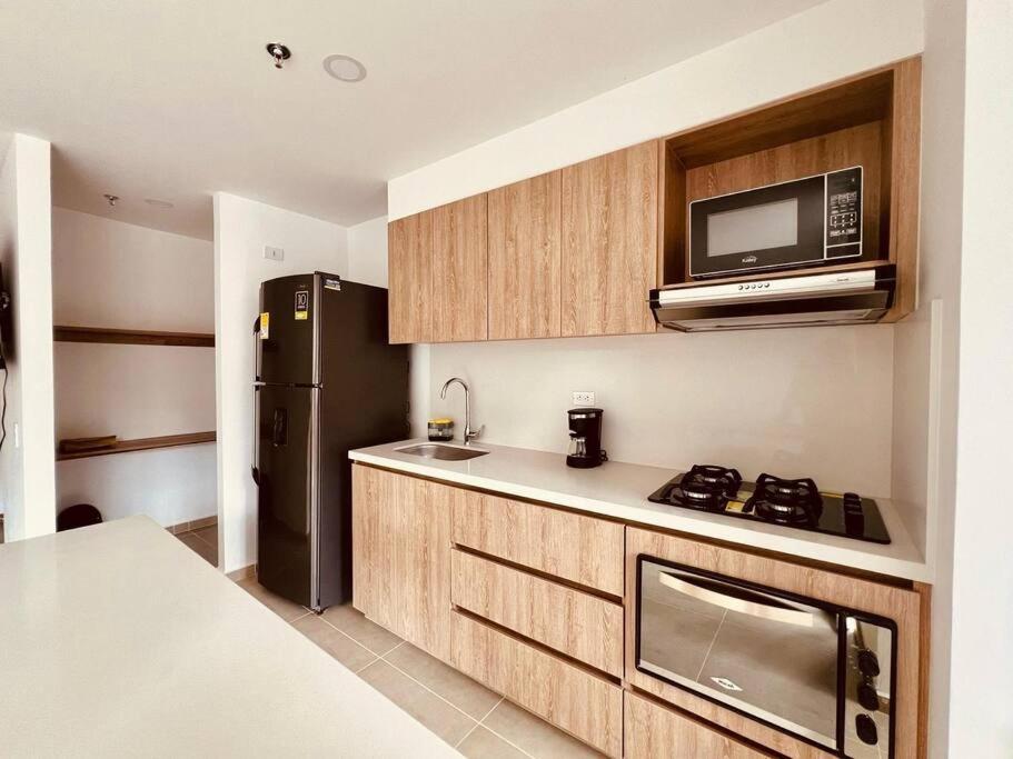 eine Küche mit einem schwarzen Kühlschrank und einer Mikrowelle in der Unterkunft Medellin: Cozy Apat with City View in Envigado