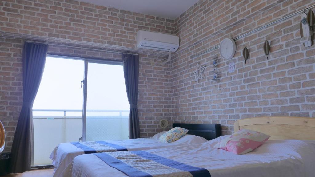 two beds in a room with a brick wall at Grandioso Wimbel Nago - Vacation STAY 13034 in Nago