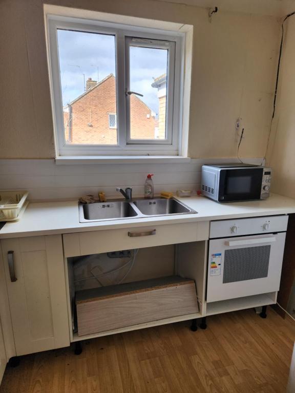 a kitchen with a sink and a microwave and a window at 88 in Wolverton