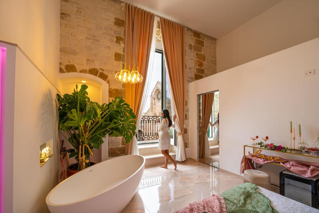 Una mujer está caminando en un baño con bañera en Casa Apuliae Bed & breakfast, en Bitonto
