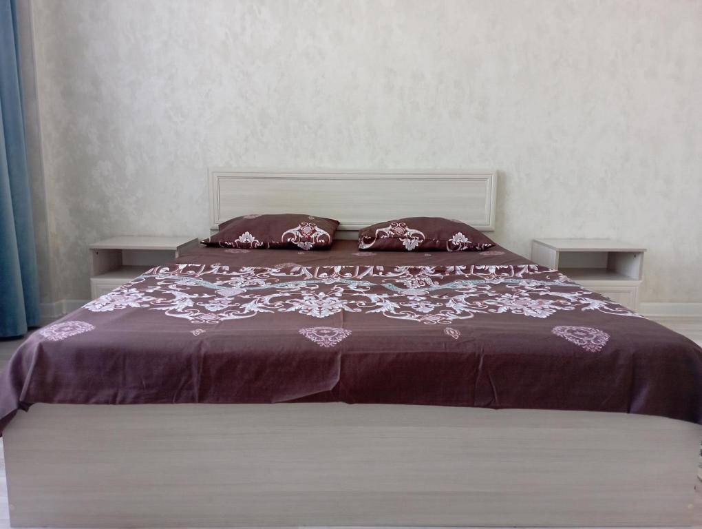 a bed with a purple comforter and pillows on it at ЖК Арай in Aktobe