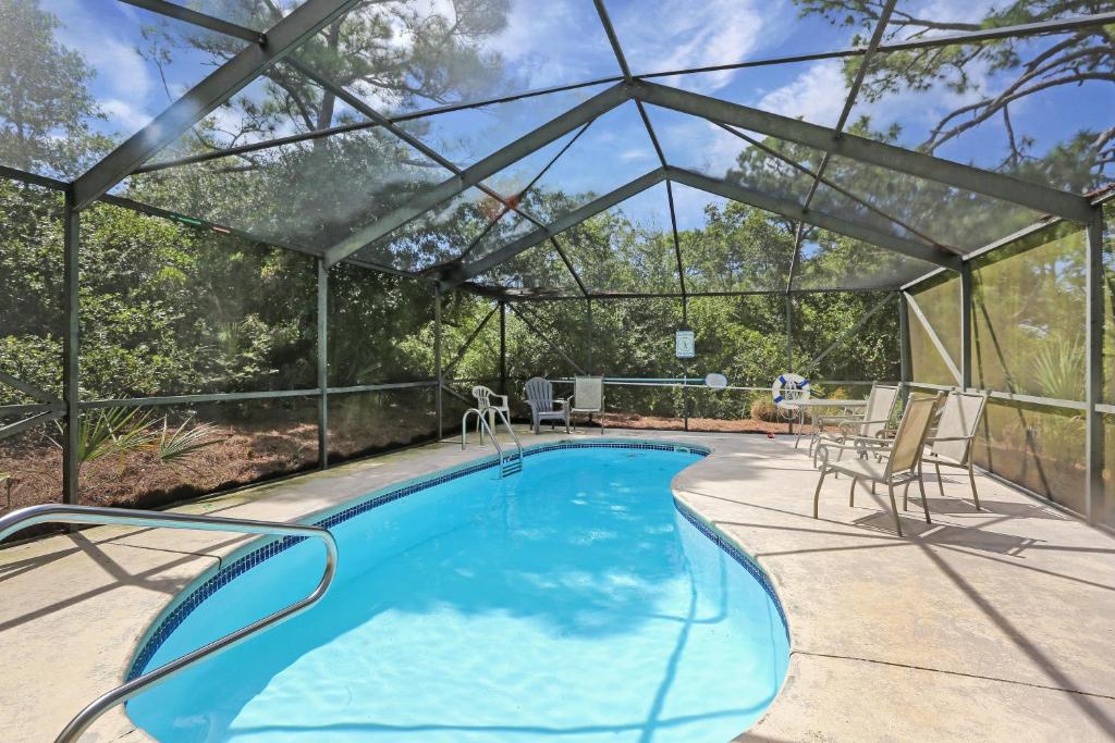 a swimming pool with a pergola and chairs next to it at Cape Palms in Cape San Blas
