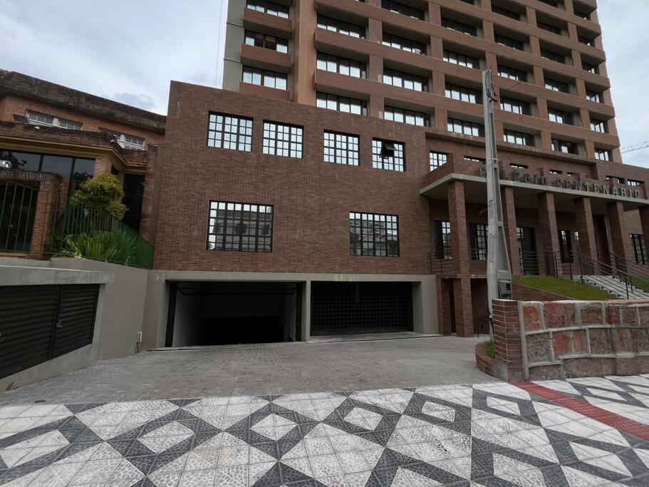 a large brick building with a parking lot in front of it at Studio no centro, novo com garagem in Santa Maria