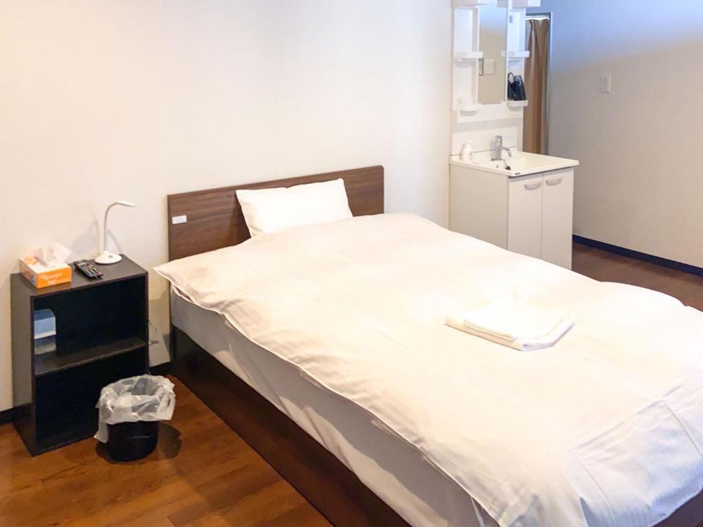 a bedroom with a large white bed with a sink at Nomura Building Parkside - Vacation STAY 34551v in Fuji