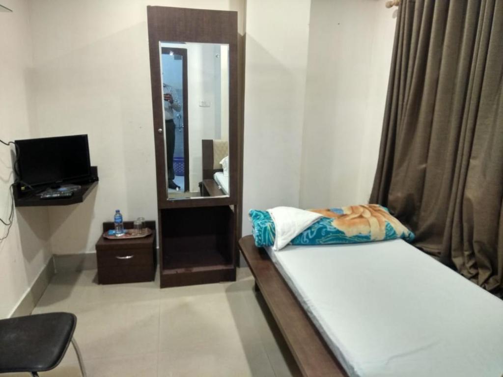um pequeno quarto com uma cama e um espelho em Lemon house em Guwahati