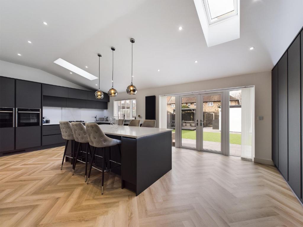 una cocina con armarios negros y una isla con taburetes. en Luxury Modern Spacious House, en Hull