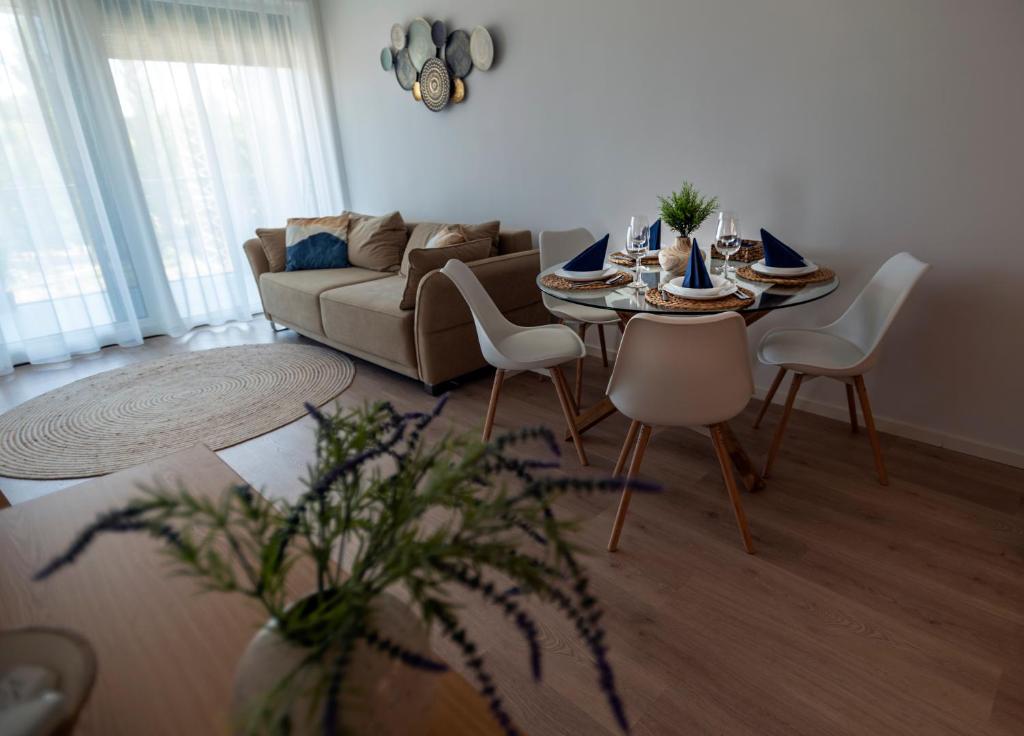 sala de estar con mesa, sillas y sofá en Mistral Residence 308, en Balatonföldvár
