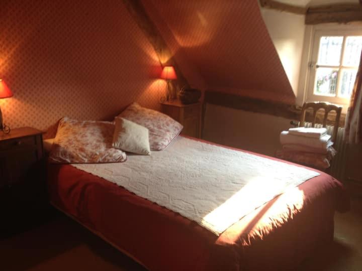 a bedroom with a bed with two pillows and a window at Gîtes du Manoir de la Porte in Les Authieux-sur-Calonne