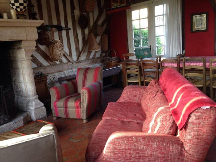 a living room with two red couches and a fireplace at Gîtes du Manoir de la Porte in Les Authieux-sur-Calonne