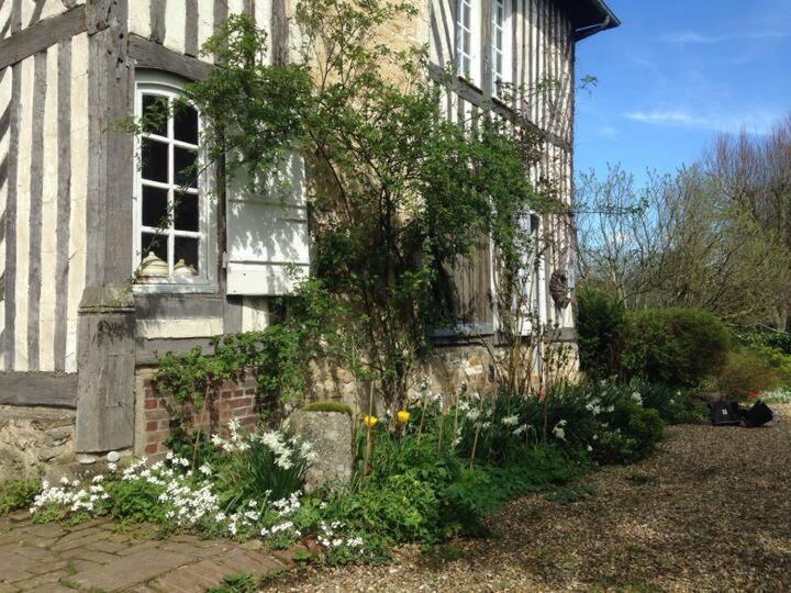 an old house with flowers in front of it at Gîtes du Manoir de la Porte in Les Authieux-sur-Calonne
