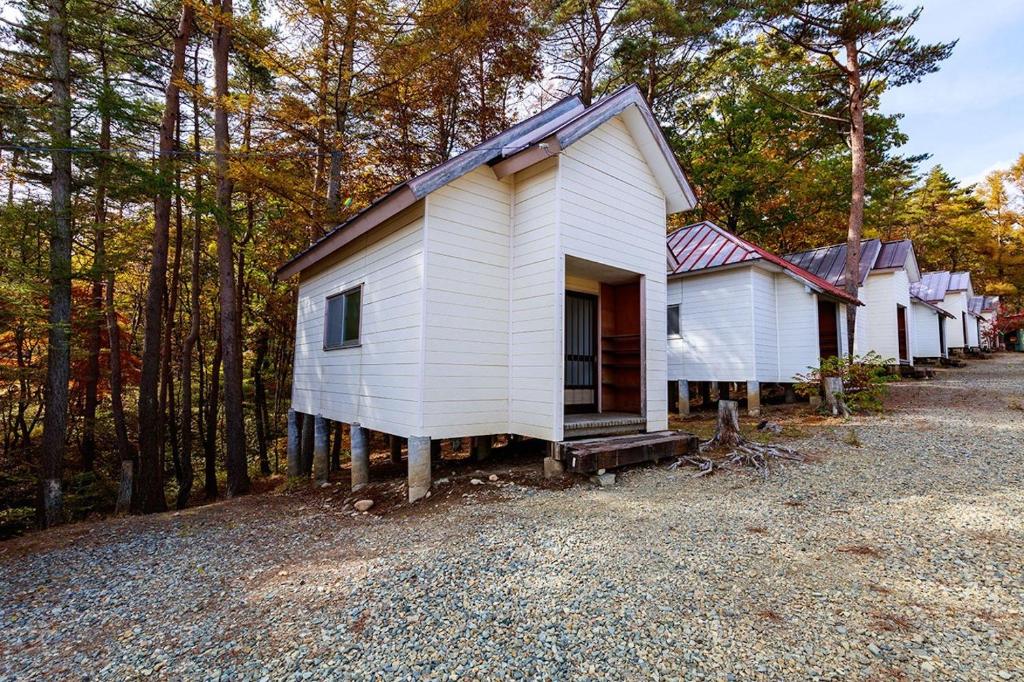 una pequeña casa blanca en medio de un bosque en Shinei Kiyosato Campsite - Vacation STAY 15467v, en Hokuto