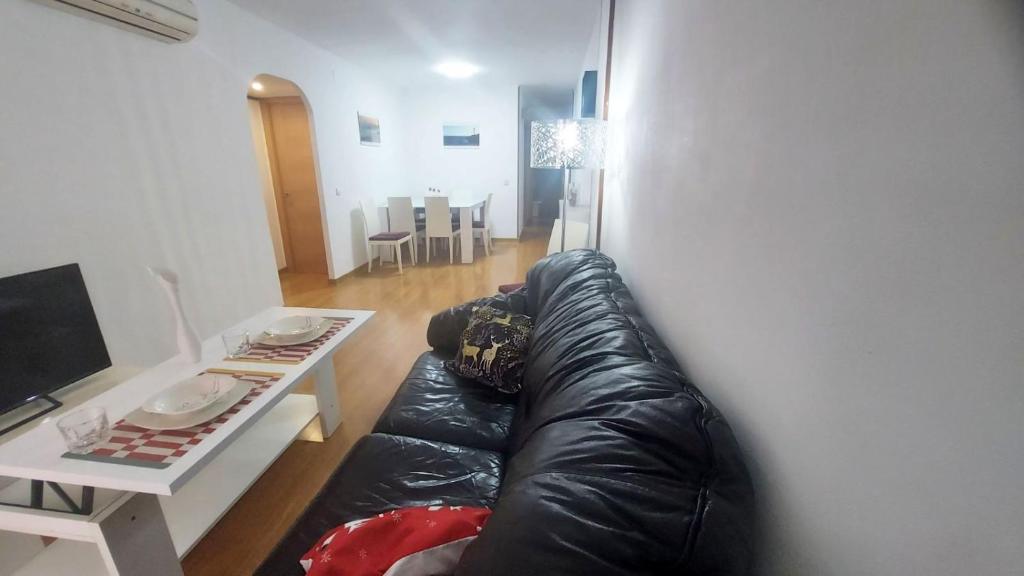 sala de estar con sofá de cuero negro y mesa en Mar & Aventura, en Torredembarra