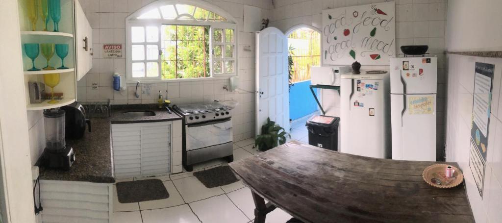 a kitchen with white appliances and a wooden bench in it at Onça da Praia Hostel in Vitória