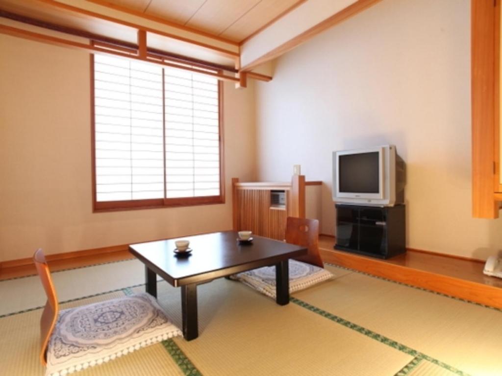uma sala de estar com uma mesa e uma televisão em Nakanoyu Onsen Ryokan - Vacation STAY 06783v em Matsumoto