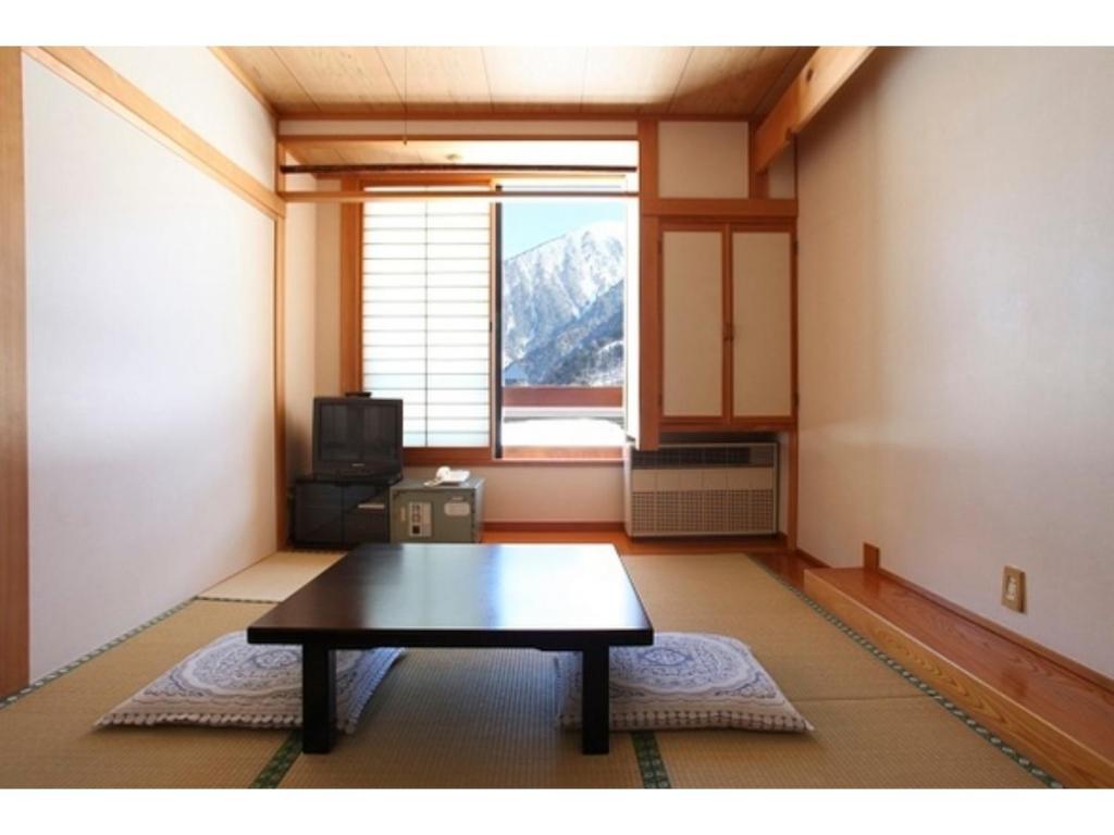 Nakanoyu Onsen Ryokan - Vacation STAY 07485v في ماتسوموتو: غرفة معيشة مع طاولة ونافذة