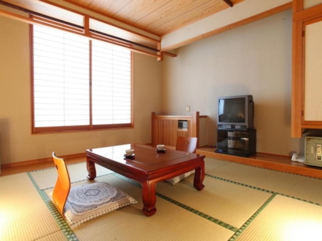 uma sala de estar com uma mesa e uma televisão em Nakanoyu Onsen Ryokan - Vacation STAY 06732v em Matsumoto