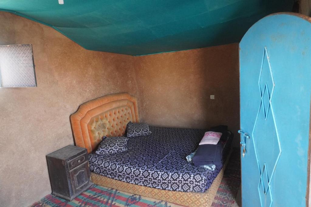 1 dormitorio pequeño con 1 cama y techo azul en Green Camp Sahara, en Mhamid