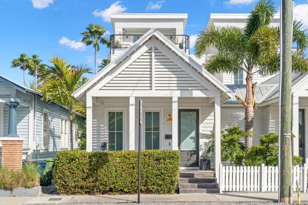 a white house with a white fence and palm trees at Casa Cohiba - Ybor City Townhouse in Tampa