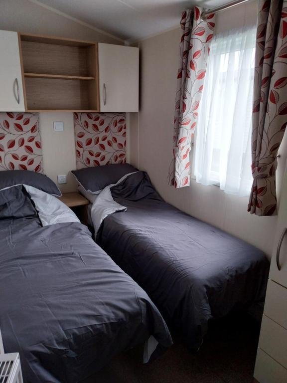 a bedroom with two beds and a window at Cordy's Caravan in Mablethorpe