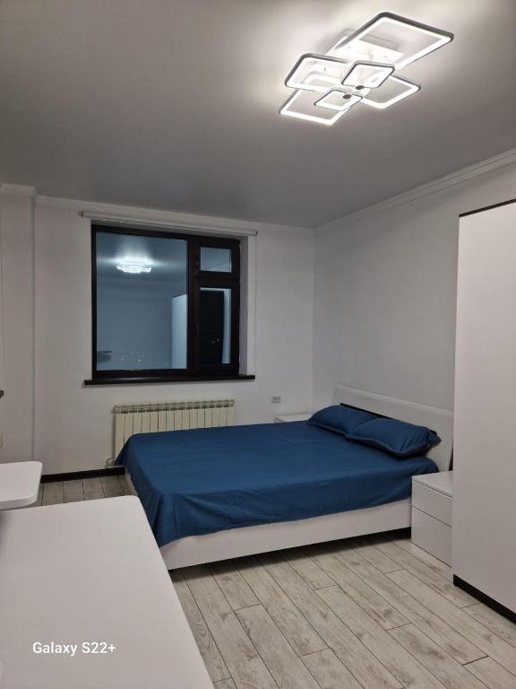 um quarto com uma cama azul e uma janela em ЖК Актобе Ажары em Aqtöbe