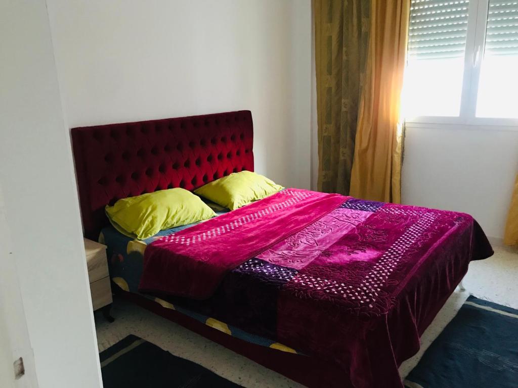 突尼斯的住宿－Le Narjess Appartement Tunis，一间卧室配有一张带红色床头板和黄色枕头的床。