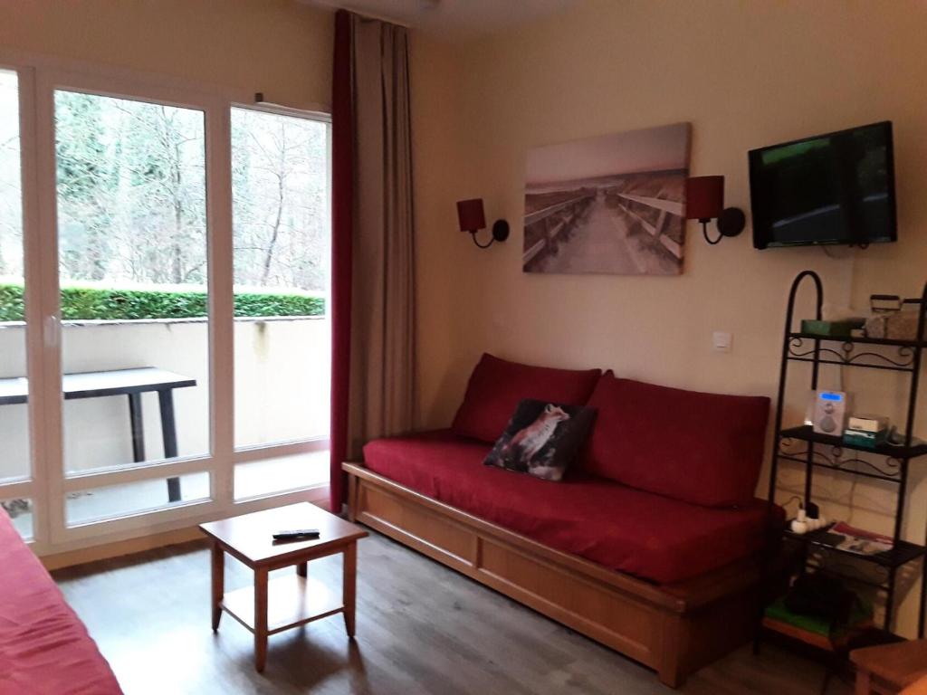 sala de estar con sofá rojo y ventana grande en Résidence Les Rives de L'Aure - maeva Home - 2 Pièces 6 Personnes Sélectio 60 en Saint-Lary-Soulan