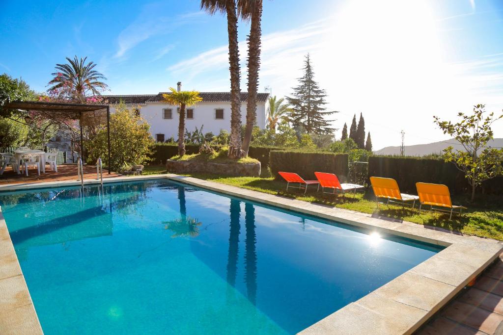 ein Pool mit orangefarbenen Stühlen und ein Haus in der Unterkunft Cortijo Navas in Cómpeta