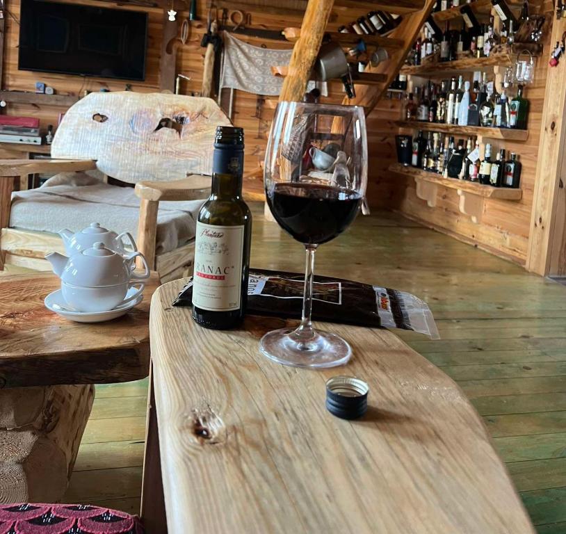 a bottle of wine and a glass on a wooden table at Black Wood in Žabljak