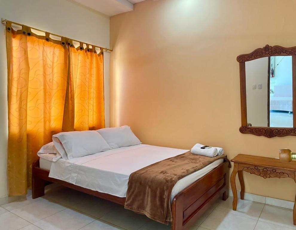 Dormitorio pequeño con cama y espejo en Hostal Doña Nancy en Mompox