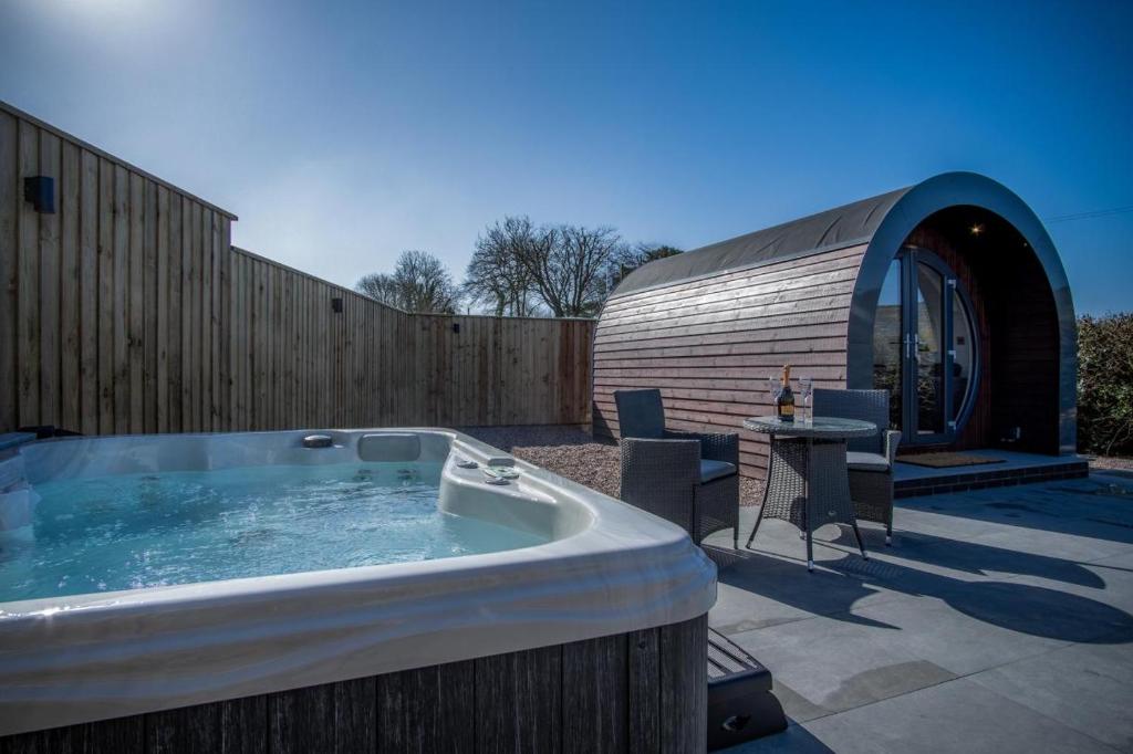 a hot tub on a patio with a circular building at Bracken Burrows - 1 Bedroom Pod - New Hedges in New Hedges