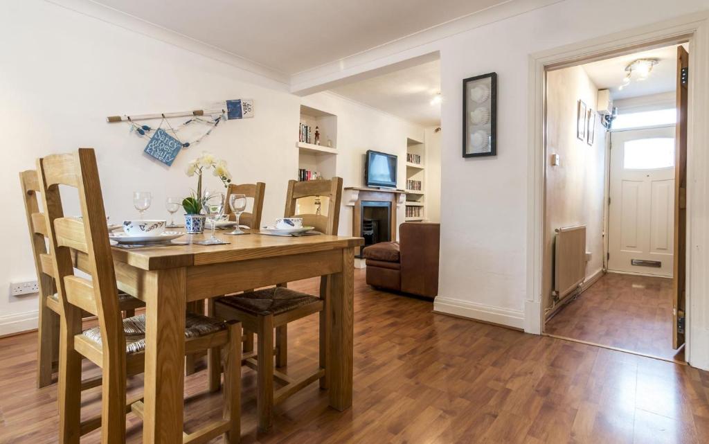 a dining room with a table and a living room at Shell Cottage - 2 Bedroom Holiday Home - Tenby in Tenby