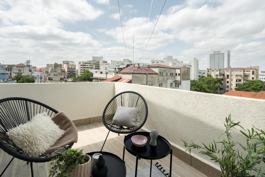 a balcony with two chairs and a view of a city at Pitar Mos - Downtown Bucharest in Bucharest