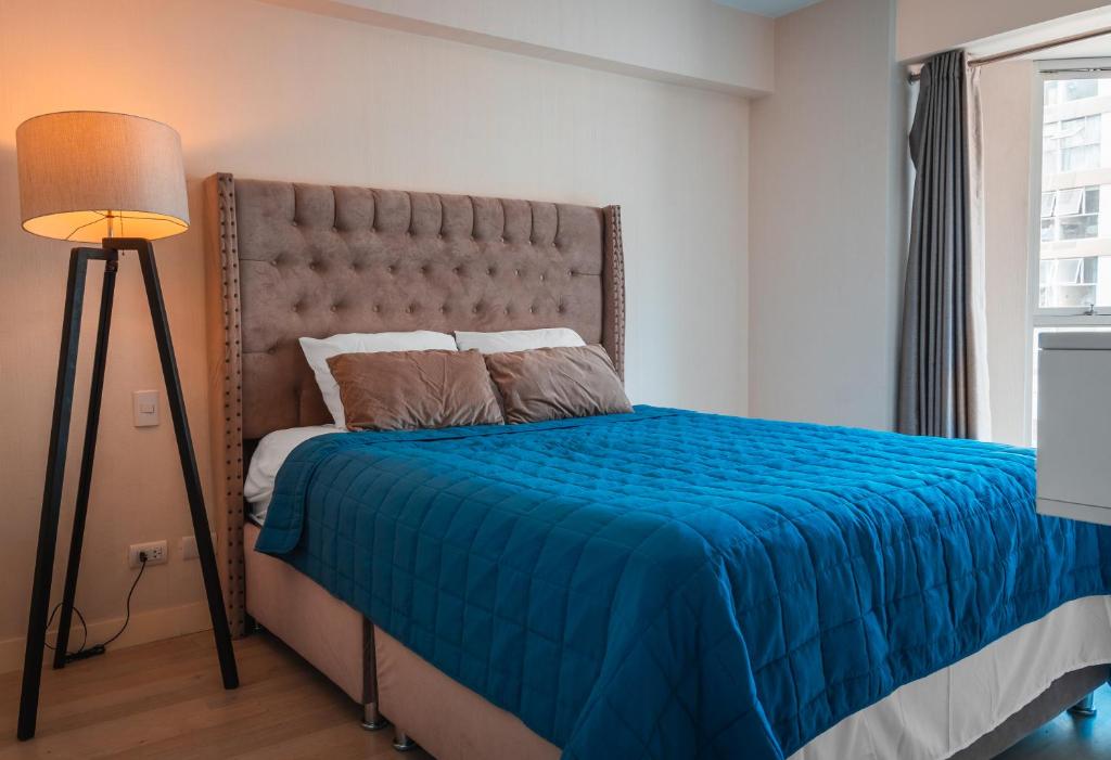 una camera da letto con un letto con una coperta blu e una lampada di Departamento con vista lateral al mar a Lima