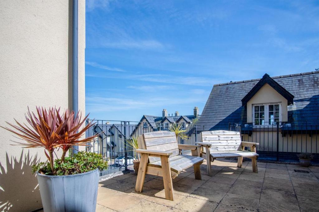 - 2 chaises en bois et une table sur la terrasse dans l'établissement Minarvon - 2 Bedroom Apartment - Saundersfoot, à Saundersfoot