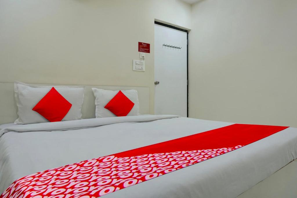 a large white bed with red pillows on it at Flagship 81482B Happy Homely Stay in Pune