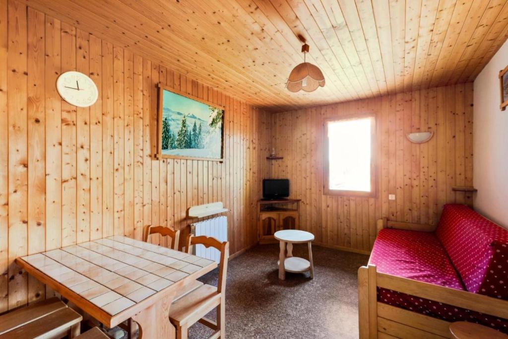 Zimmer mit einem Tisch und einem roten Sofa in der Unterkunft Chalet le Séchet - Maeva Particuliers - 2 Pièces 4 personnes Confort 140619 in Bellentre