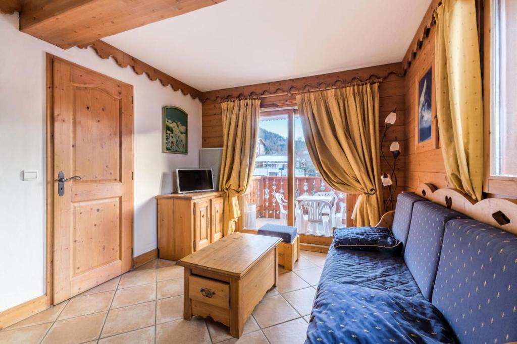 ein Wohnzimmer mit einem blauen Sofa und einem Fenster in der Unterkunft Résidence Les Fermes du Soleil - maeva Home - 3 Pièces 6 Personnes Sélection MAE-4102 in Les Carroz d'Araches