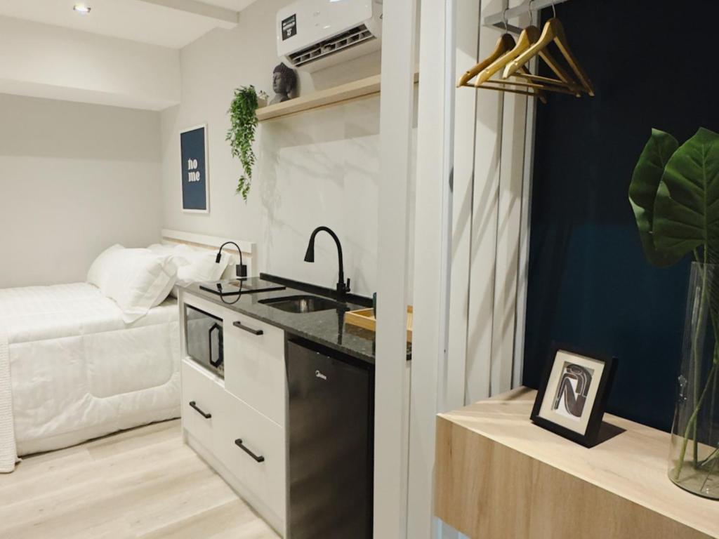 a kitchen with a sink and a living room with a couch at Apê Pátio Paulista in São Paulo
