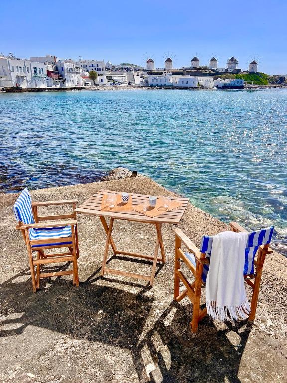 a table and two chairs sitting next to the water at mills suites mykonos in Mýkonos City