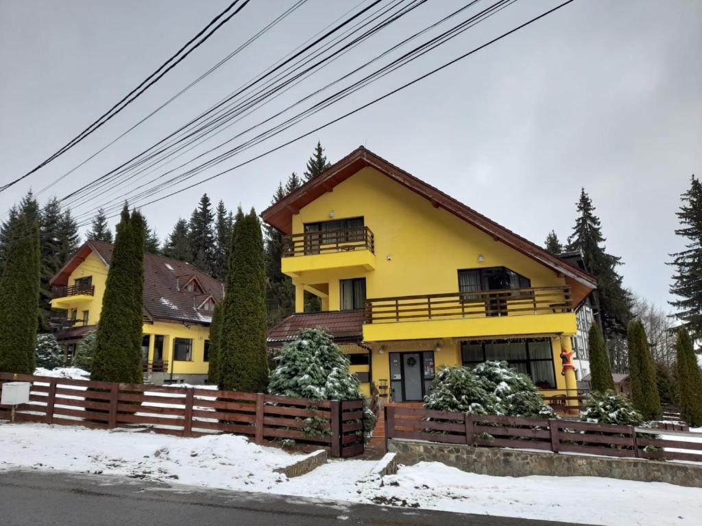 a yellow house with a fence in the snow at Vila Doru Predeal in Predeal