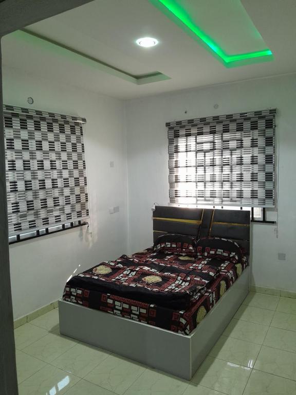 - une chambre avec un lit dans une chambre avec 2 fenêtres dans l'établissement Tradebybata Homes, Abeokuta around FUNAAB, à Abeokuta