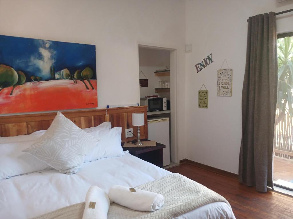 a bedroom with a white bed with a painting on the wall at Sweet Dreams Guest House Schweizer Reneke in Schweizer-Reineke
