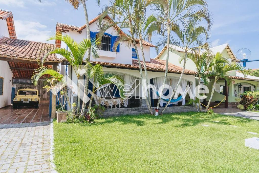 une maison avec des palmiers devant elle dans l'établissement Casa a 10 min da Praia do Forte, em Cabo Frio, à Cabo Frio