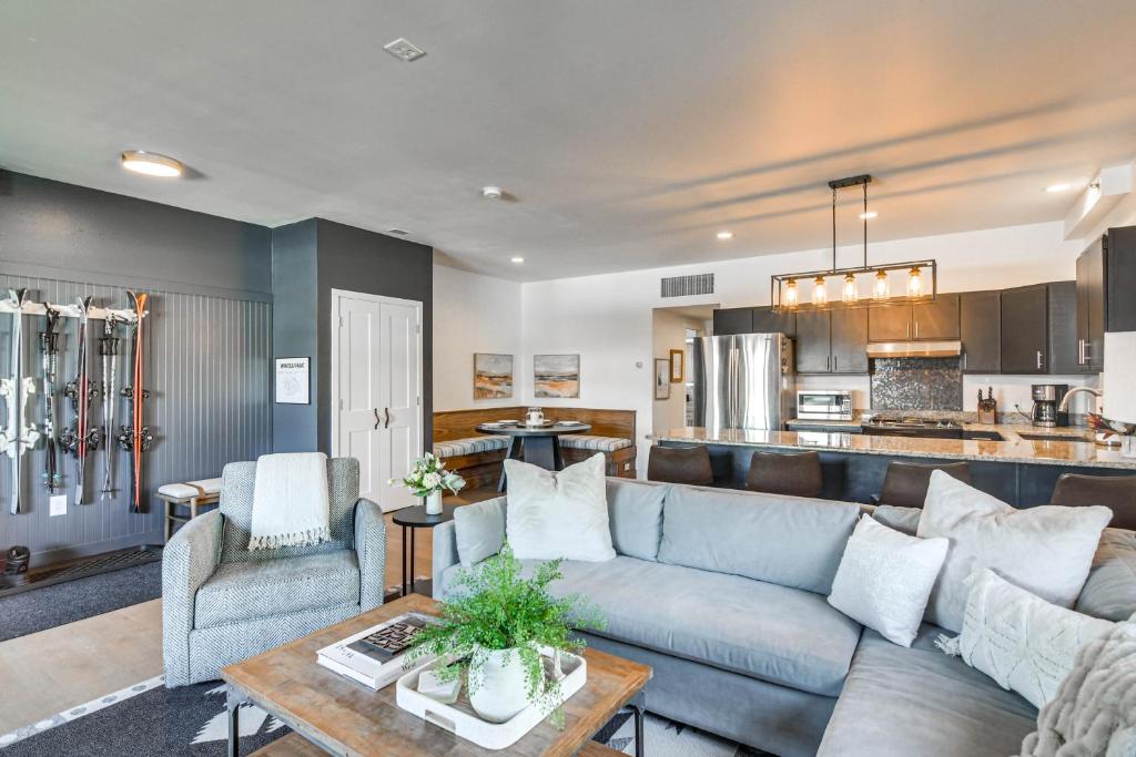 a living room with a blue couch and a kitchen at Downtown Winter Park Condo with Free Bus to Ski Base in Winter Park